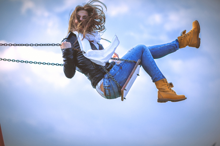 Young woman having fun swinging on a spring sunny day